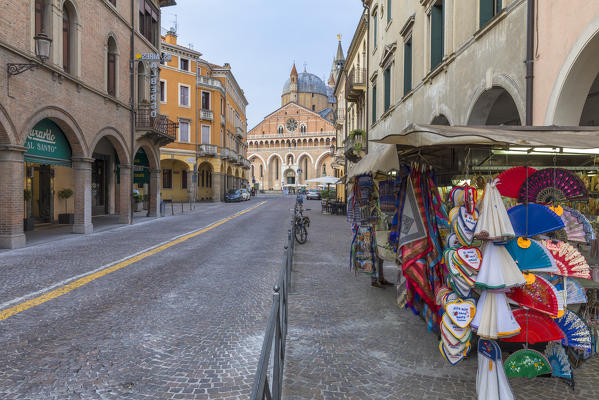 Central street in Padua, Italy looking to the Basilica of St Anthony with brightly colored garments for sale on the side walk in the foreground, veneto, italy, europe