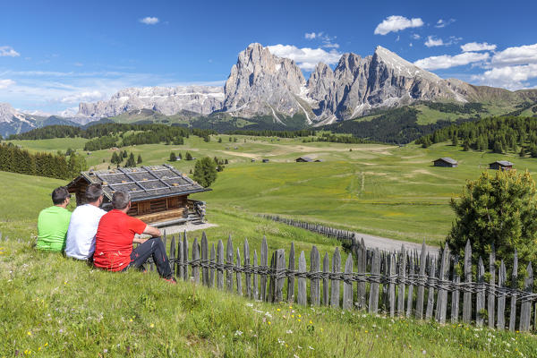 Europe, Italy, South Tyrol, Bolzano, Dolomites, Three hikers seated to admire the landscape on the mountain of siusi, with colorful t-shirts like the colors of the Italian flag