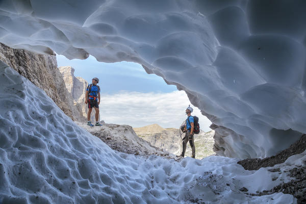 Italy, South Tyrol, Hochpustertal, Sexten. Snow cave in the summer season along the Alpinisteig / Strada degli alpini via ferrata, Sexten Dolomites