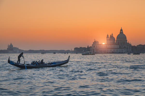 Gondola on the Grand Canal at sunset with Basilica of Saint Mary of Health in background, Punta della Dogana, Venice, Veneto, Italy