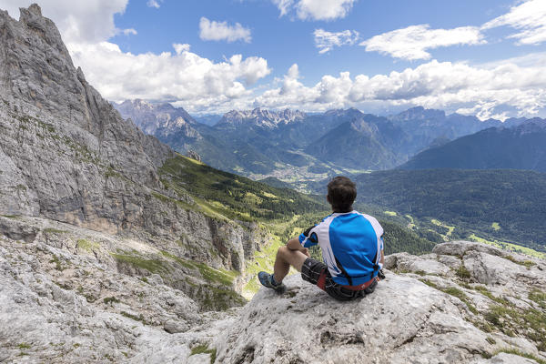 Europe, Italy, Veneto, Agordino, Mountaineer observes the panorama at the end of the ferrata Stella Alpina on Mount Agner, Pale di San Martino, Dolomites