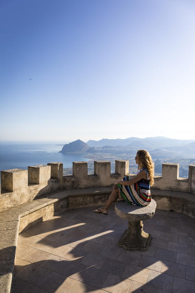 A girl walking in Erice, a small village near Trapani, Western side of Sicily, Italy. San Vito lo Capo on the background.