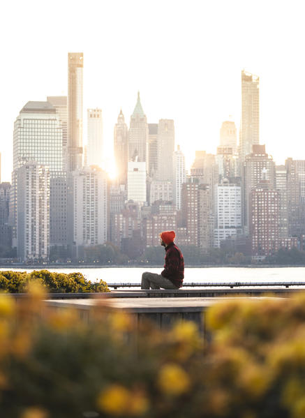 A man admiring Manhattan skyline at sunrise from New Jersey coastline. New York, USA.