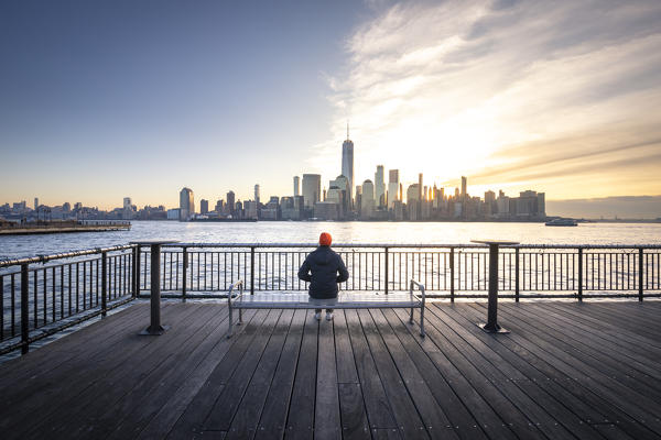A man admiring Manhattan skyline at sunrise from New Jersey coastline. New York, USA.