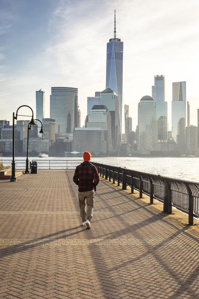 A man admiring Manhattan skyline at sunrise from New Jersey coastline. New York, USA.
