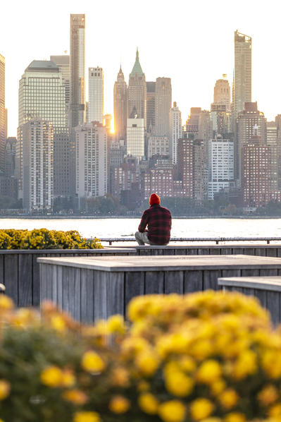 A man admiring Manhattan skyline at sunrise from New Jersey coastline. New York, USA.