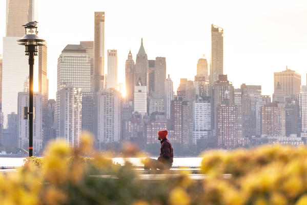 A man admiring Manhattan skyline at sunrise from New Jersey coastline. New York, USA.