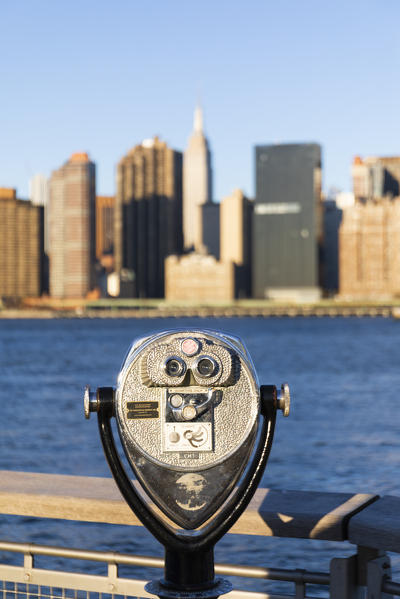A telescope to see Manhattan skyline from Queens coastline. New York, USA