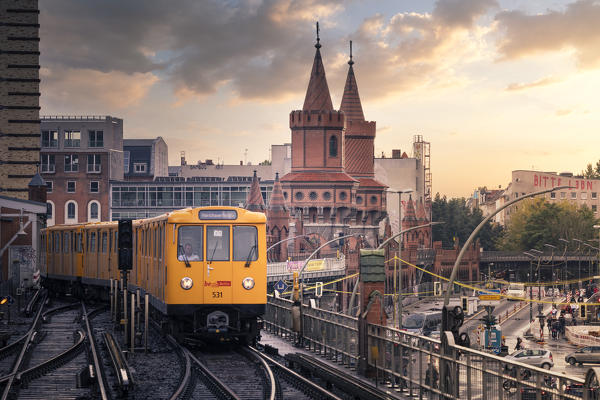 Panoramic view of Berliner U-Bahn with Oberbaum Bridge in the background in golden evening light at sunset. Friedrichshain-Kreuzberg district, Berlin, Germany