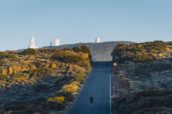 Woman walking in Teide National park with Teide observatory on the background. Tenerife, Canary Islands, Spain