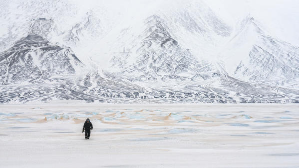 A man walks in Billefjorden, after orange sand from the Sahara desert was blown north up to Spitsbergen, Svalbard, in late 
winter.