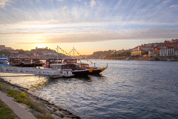 foto  - Sunset on Port wine boats moored on the south bank of Douro River, whit Arrábida Bridge and Porto old town on the background, Vila Nova de Gaia, Porto district, Norte Region, Portugal