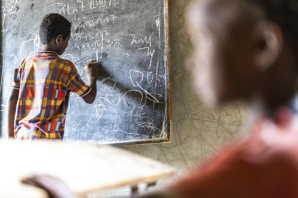 foto  - Young boy writing on blackboard at school, Melabday, Asso Bhole, Danakil Depression, Afar Region, Ethiopia, Africa