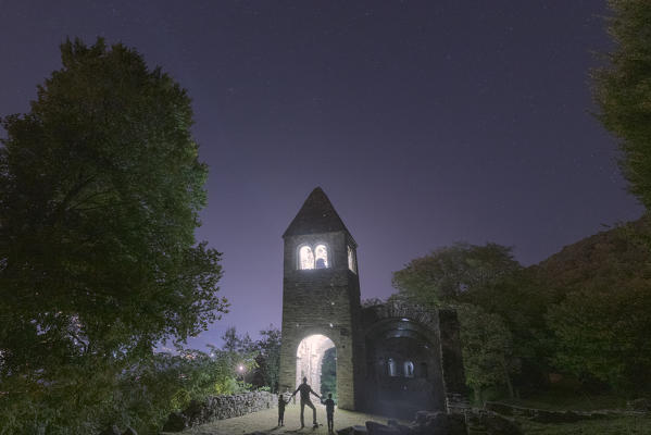 foto  - Cheerful man with two little boys sons admiring the illuminated abbey of San Pietro in Vallate, Valtellina, Lombardy, Italy
