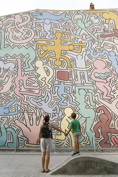 foto  - Mother and little boy child admiring the Keith Haring artistic mural named Tuttomondo, Pisa, Tuscany, Italy