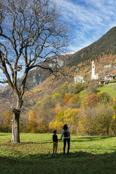 foto  - Rear view of mother with cute son admiring the alpine village of Soglio in autumn,  Graubunden canton, Switzerland