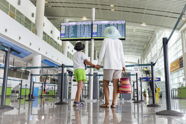 foto  - Cute little boy and mother holding hands while checking the schedule of flight at the departure area of airport