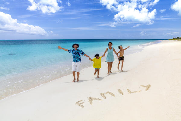 foto  - Happy family with two little boys smiling at camera next to the word family written on sand, Antigua & Barbuda, Caribbean