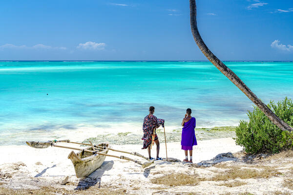 foto  - Couple of Maasai with dhow admiring the crystal turquoise sea standing on a white coral beach, Zanzibar, Tanzania (MR)