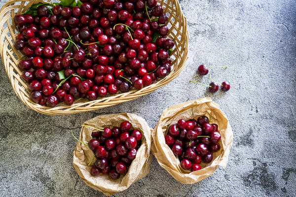 foto  - High angle view of fresh red cherries in straw basket on gray table background