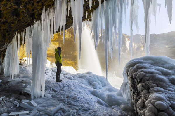 foto  - A man at Kvernufoss waterfall under stalactites, Skogar, Sudurland, Iceland, Northern Europe