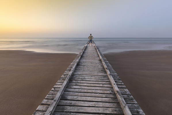 foto  - Europe, Italy, Veneto, Venice, Jesolo. A man on a wooden pier on the beach in the morning