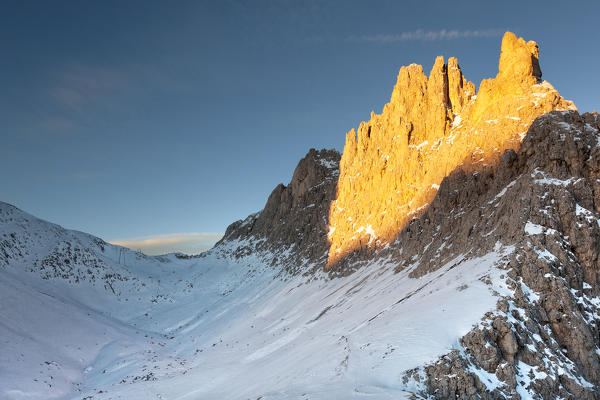 foto  - Santnerpass and Croda of King Laurin (Croda di Re Laurino) in a sunlit morning in early winter. Snow covers the entire path to the Santner pass, Rosengarten group - Catinaccio, Dolomites